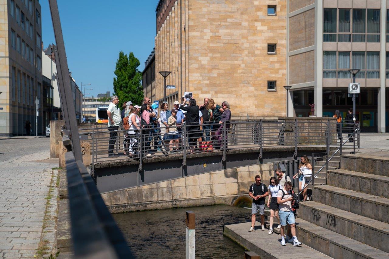 Gruppe von Menschen auf Brücke bei einer Stadtführung.