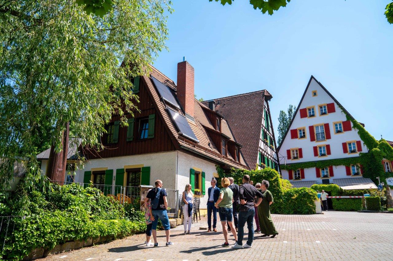 Eine Gruppe von Menschen steht vor dem Hotel Lohmühle und interesseressiert sich für die Ausführungen der Hotelinhaberin.