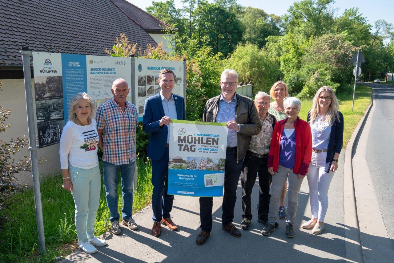 Acht Menschen mit Ankündigungsplakat zum Mühlentag 2023 vor der Hölzleinsmühle